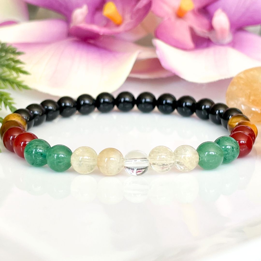Multicolored beaded bracelet on a white background with flowers in the background