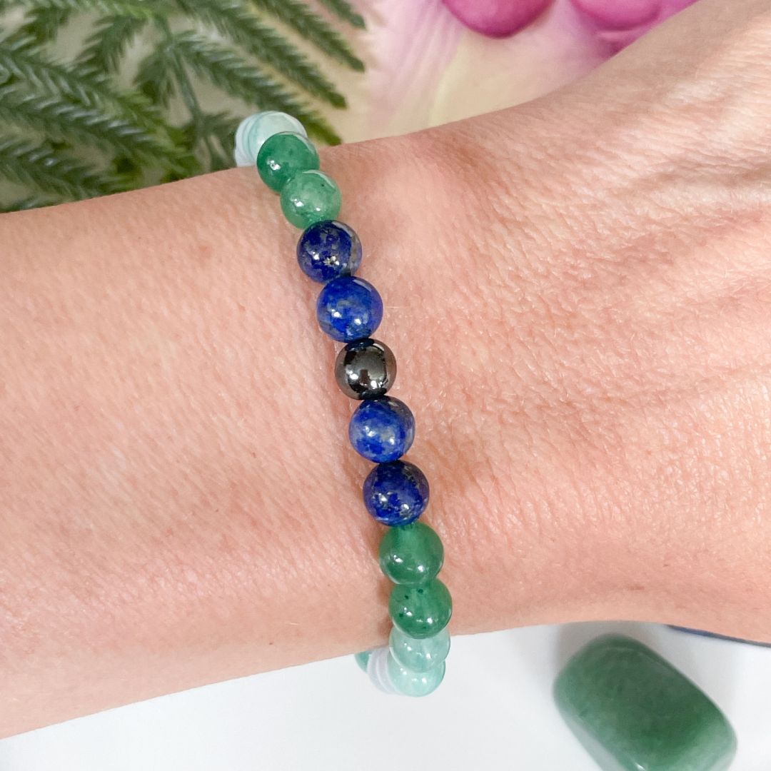 Close-up of a wrist wearing a beaded bracelet with green, blue, and black beads.