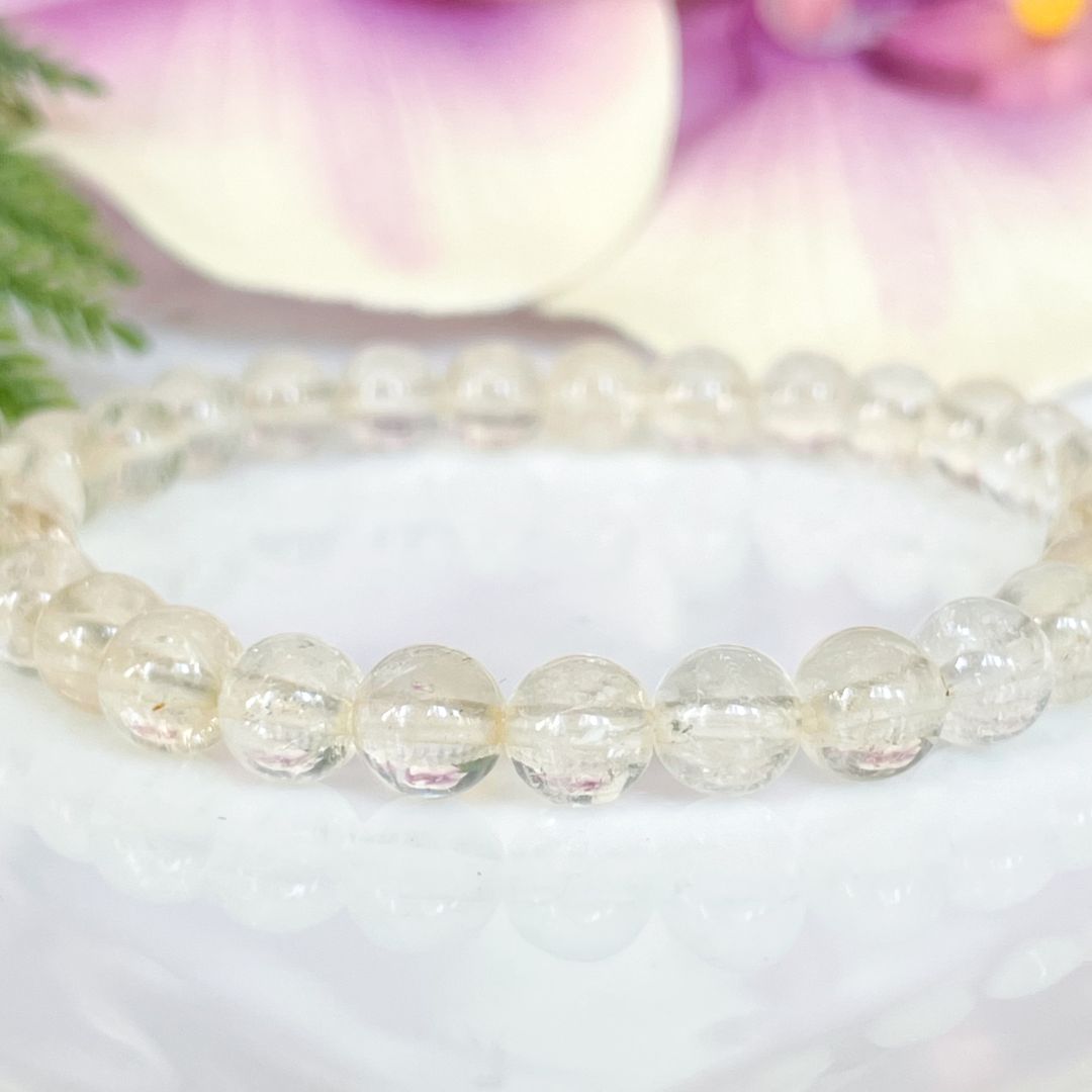Beaded bracelet on a white surface with a blurred floral background