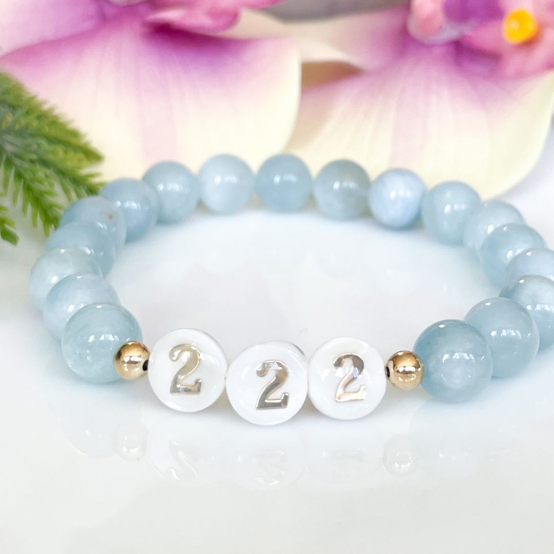 Light blue beaded bracelet with gold accents and number '2' on a white background