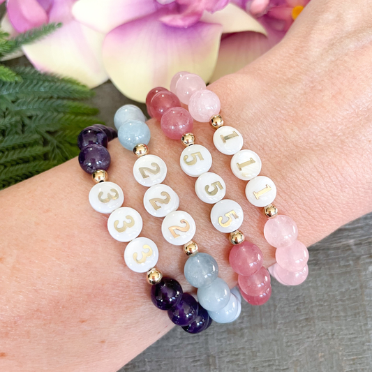 Multicolored beaded bracelets on a wrist with flowers in the background
