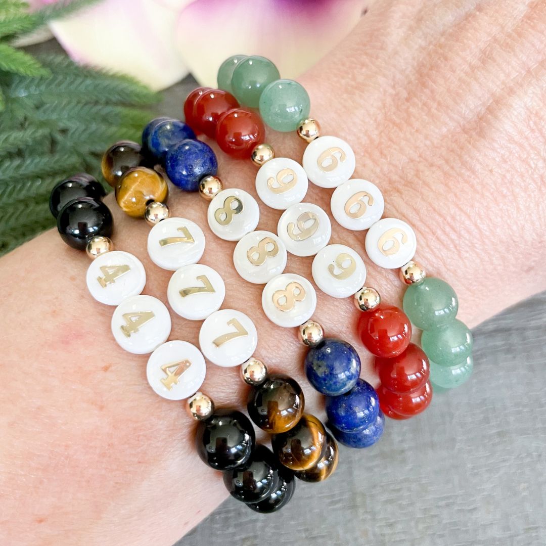 Colorful beaded bracelets on a wrist with a blurred floral background