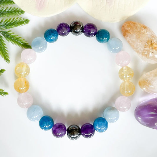 Multicolored beaded bracelet on a white surface with crystals and leaves.