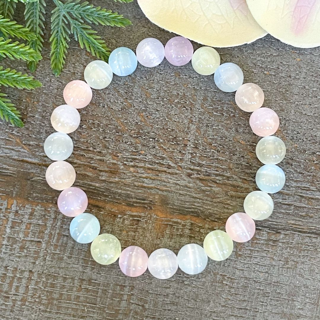 Multicolored beaded bracelet on a wooden surface with greenery