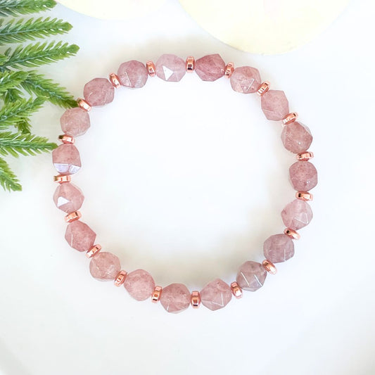 Pink beaded bracelet with rose gold accents on a white background