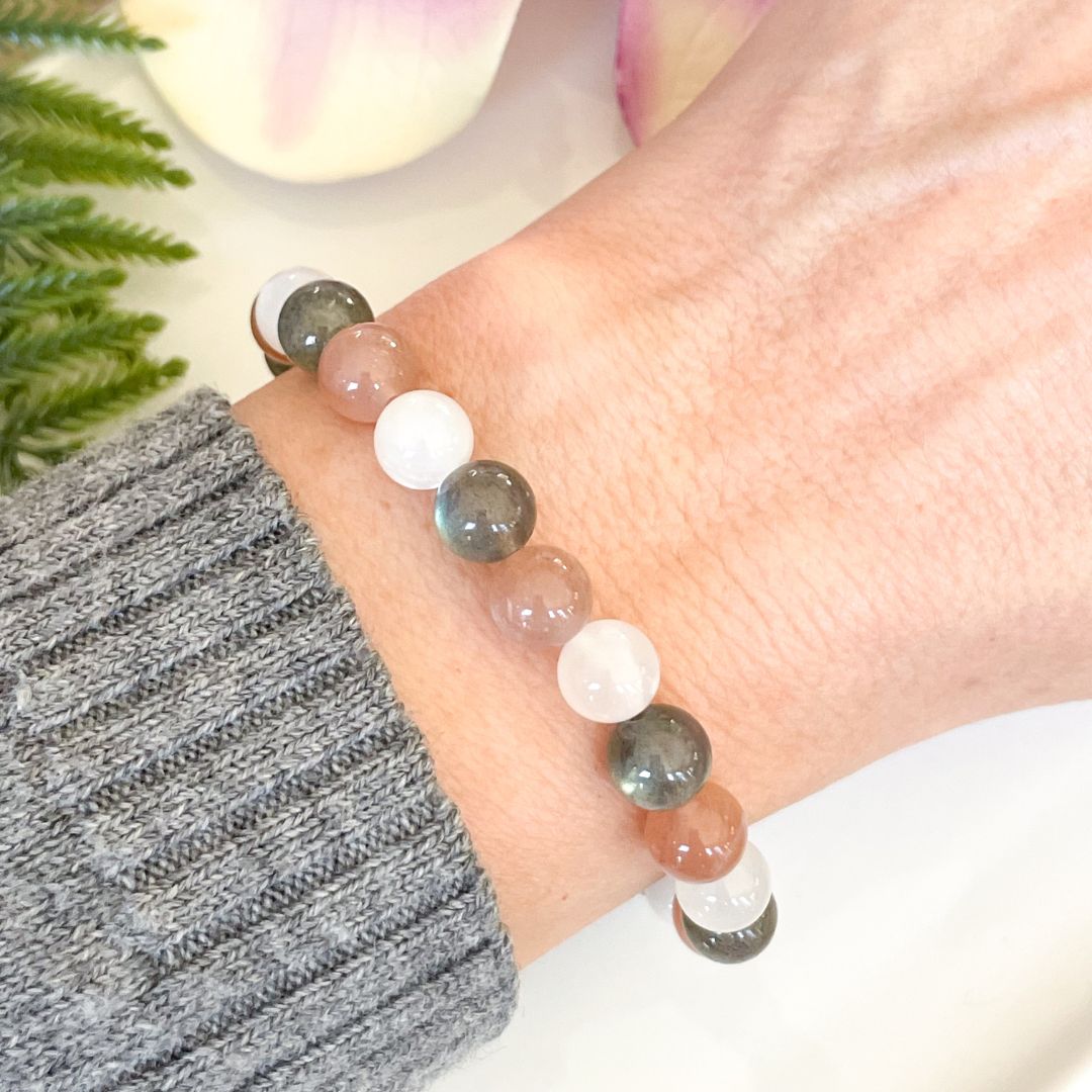 Close-up of a hand wearing a bracelet with multicolored beads on a blurred background