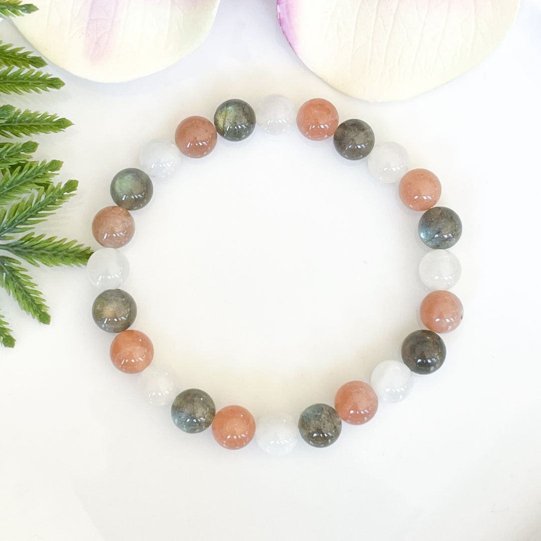 Multicolored beaded bracelet on a white background with green leaves