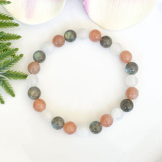 Multicolored beaded bracelet on a white background with green leaves